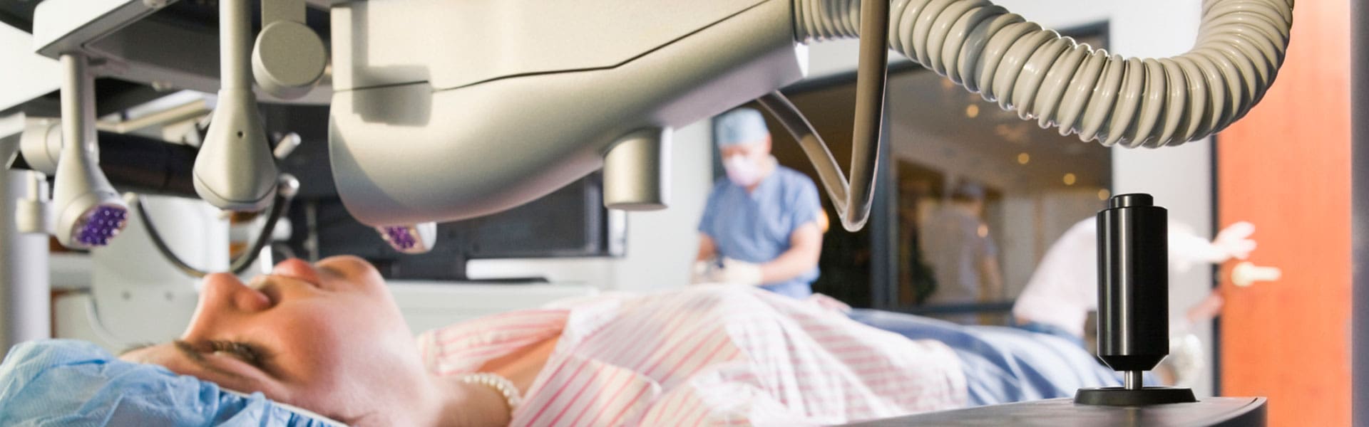 A surgeon is operating on an animal in the background.