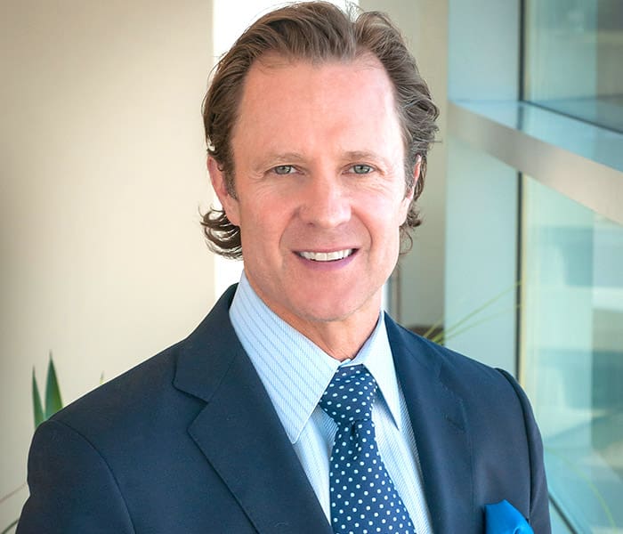 A man in suit and tie smiling for the camera.