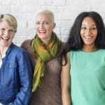 Three women standing next to each other smiling.