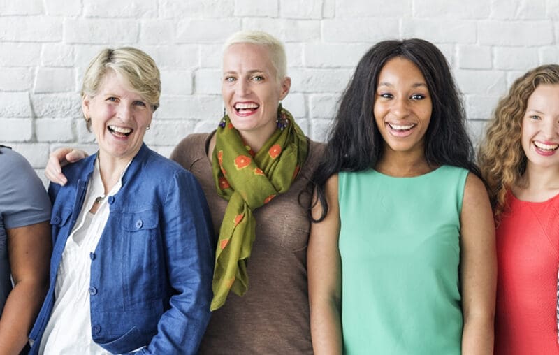 Three women standing next to each other smiling.